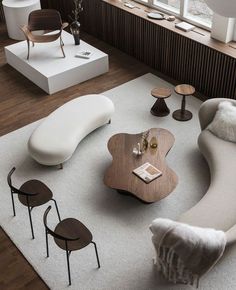 modern living room space shoot from high angle with round wooden coffe table and white round couches standing on big white rug