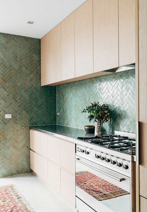 modern kitchen with light caboards and green shiny tiles