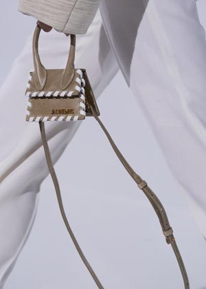 close up of tiny brown trapeze shaped Jacquemus bag with white detailing on hems