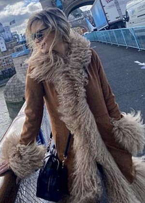 coat trends for 2022 - girl standing on london bridge wearing brown jacket with furry collar and cuffs