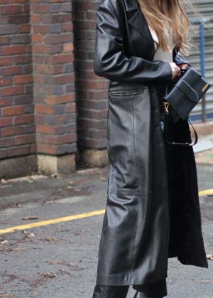 woman wearing ankle-length leather coat styled with white top, leather boots and leather straigh-legged pants