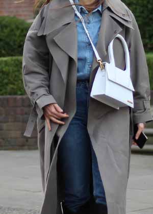 coat trends for 2022 - close up of woman walking on the street wearing trench coat and white bag