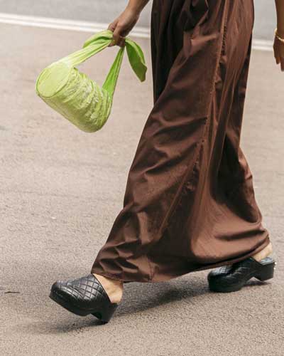 flat shoe trends summer 2022 - leather clogs styled with brown maxi and neon green fabric bag