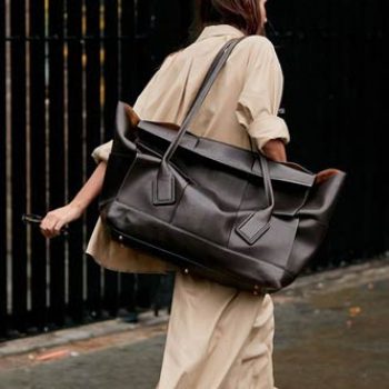 street style shoot of blogger wearing baggy cream outfit and massive brown leather bag